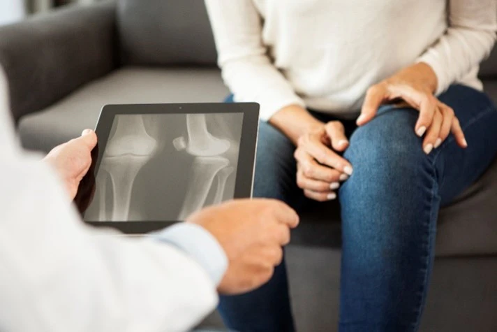 Orthopedic physician asking a patient questions about their knee replacement surgery