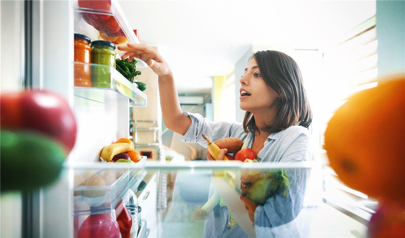 Women putting food in fridge 