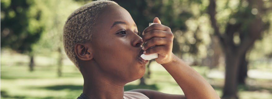 A young woman taking a breath from an inhaler